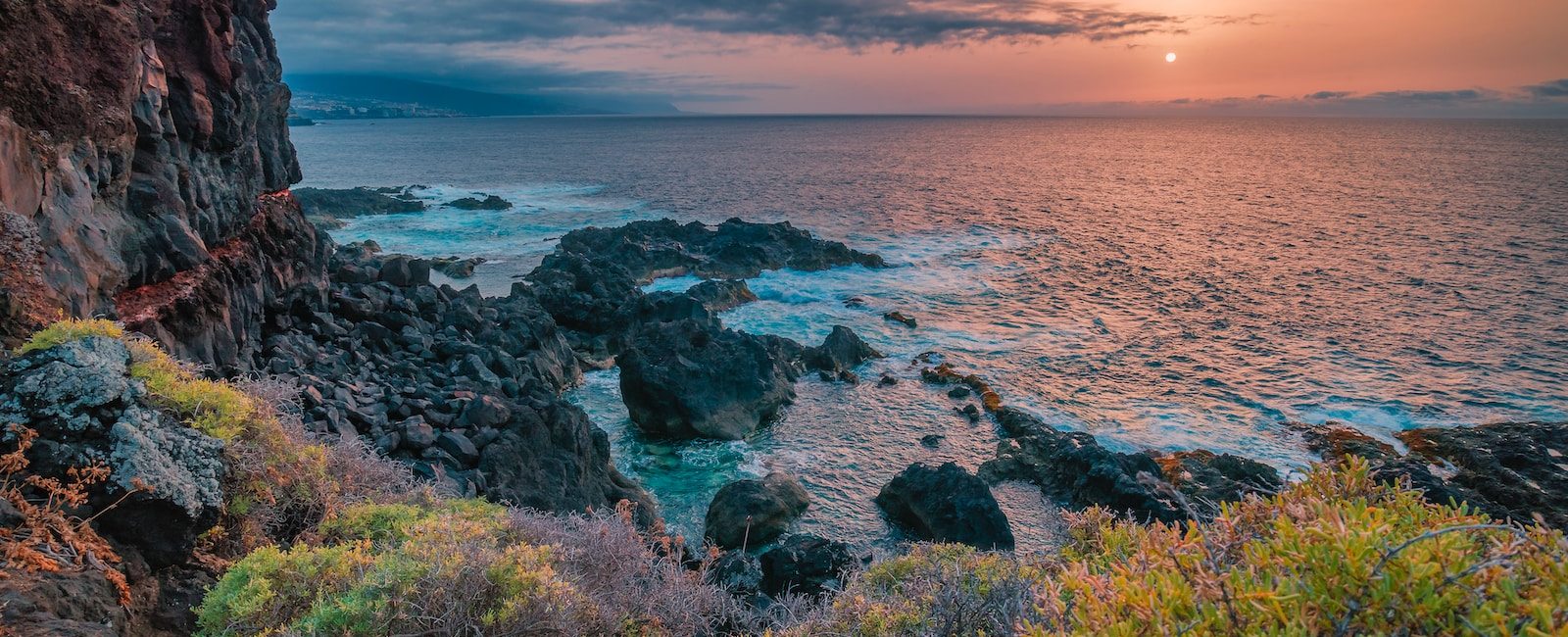 Scenic rocky coastline at sunset with vibrant sky and ocean waves in a tranquil landscape view
