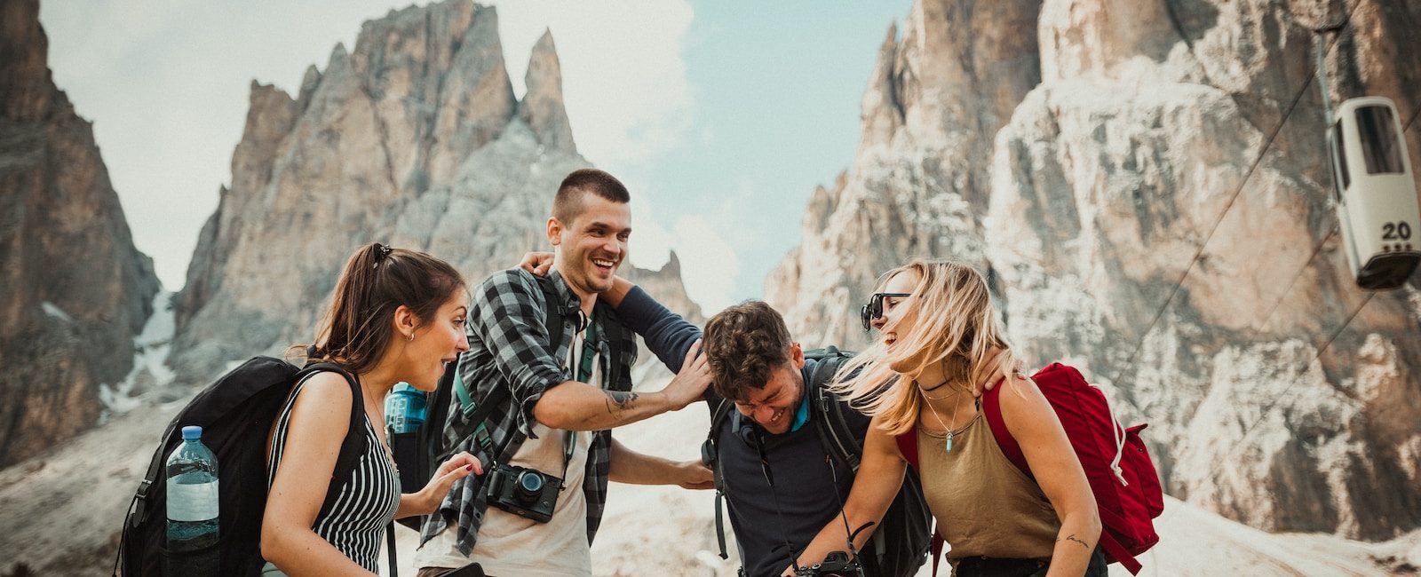 Group of friends having fun while hiking in the mountains with picturesque rocky peaks in the background