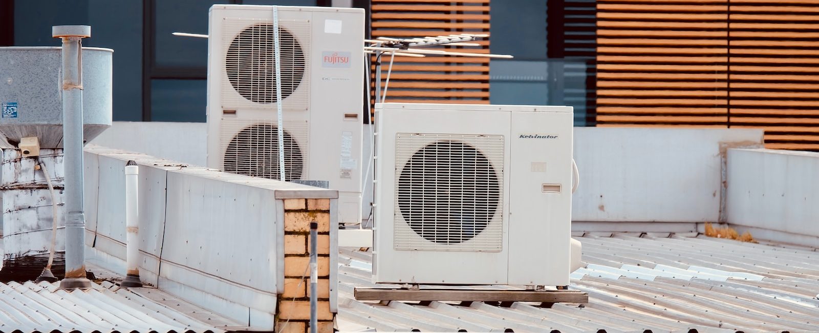Rooftop air conditioning units on urban building with brickwork and modern wood slats enhancing the structure
