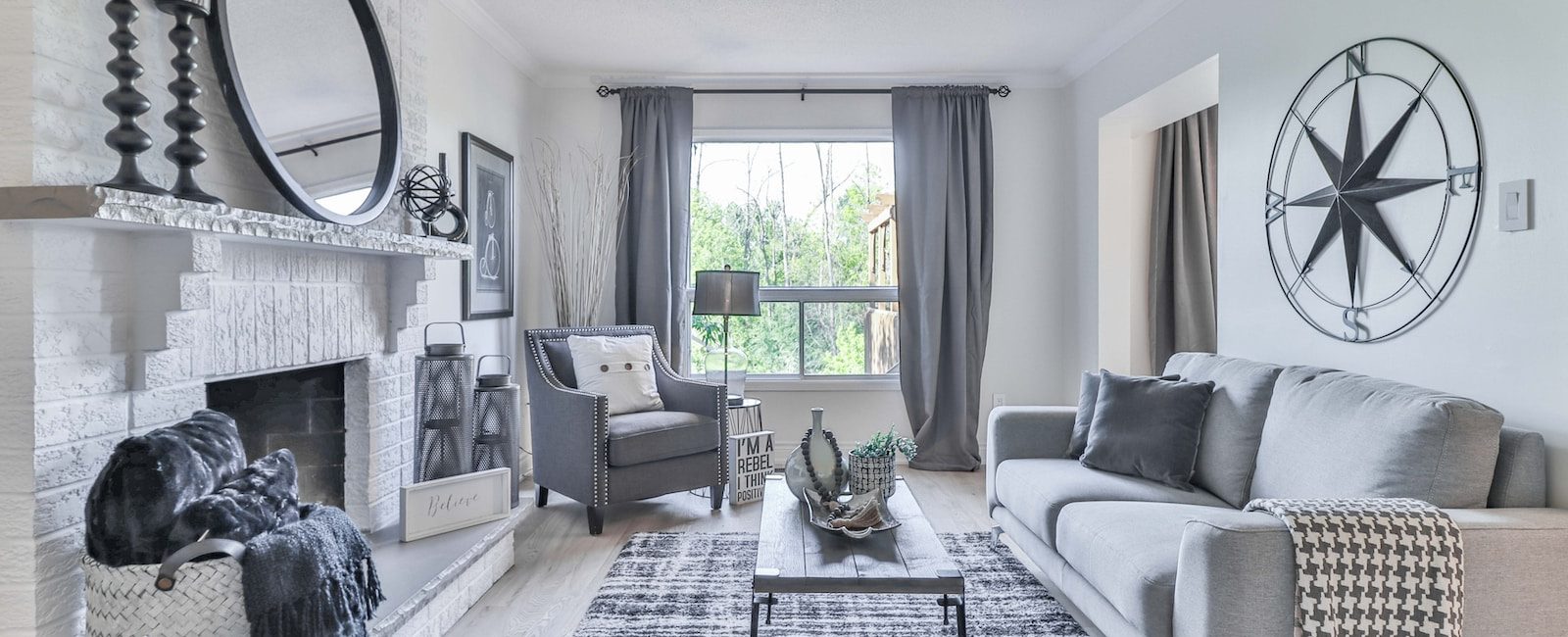 Modern living room with grey sofa, stylish decor, large window, and cozy fireplace showcasing chic interior design