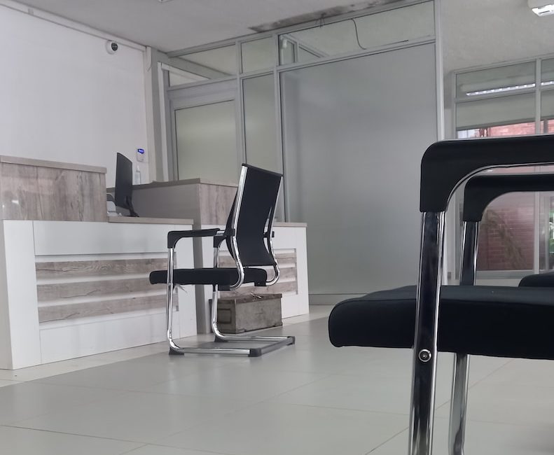Modern office reception area with chairs and desk, featuring sleek decor and natural lighting