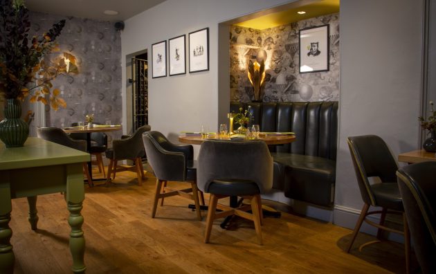 Cosy restaurant interior with modern decor, wooden floors and grey seating, softly lit for an inviting dining atmosphere