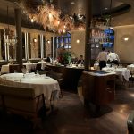 Elegant restaurant interior with round tables and dim lighting, featuring attentive staff and stylish decor