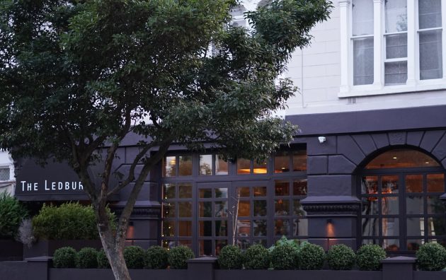 Street view of The Ledbury restaurant exterior with trees and decorative plants
