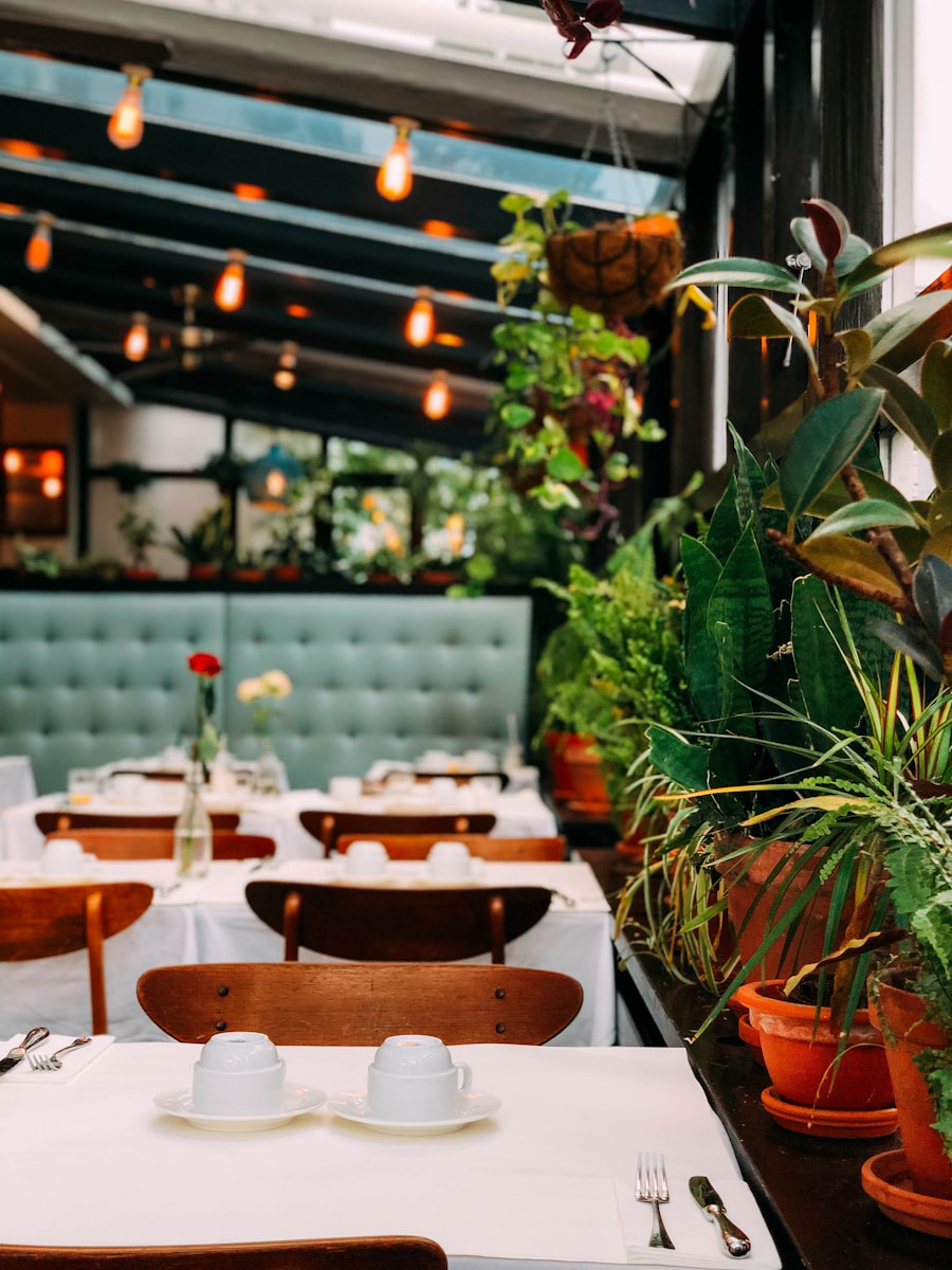 Cosy restaurant interior with tables set, potted plants, and warm hanging lights in a modern setting