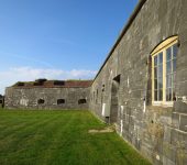 Stone fort wall and grassy landscape under a clear blue sky at historic site in England