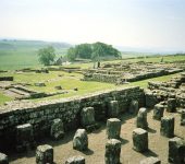 Ancient Roman ruins of Hadrian's Wall with green rolling hills and visitors exploring the historic site