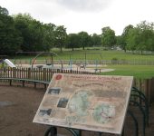 Playground in Sutton Park with archaeology information board and green landscape background